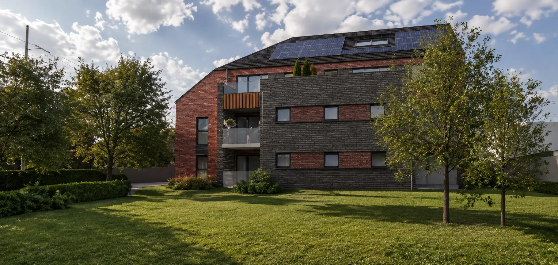 Immeuble de logements en briques rouges et noires avec balcons et toiture solaire, vue depuis le jardin