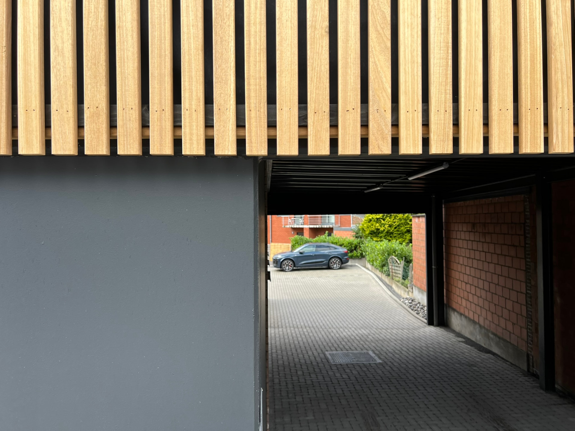Détail du bardage en lattes de bois et perspective vers le parking intérieur