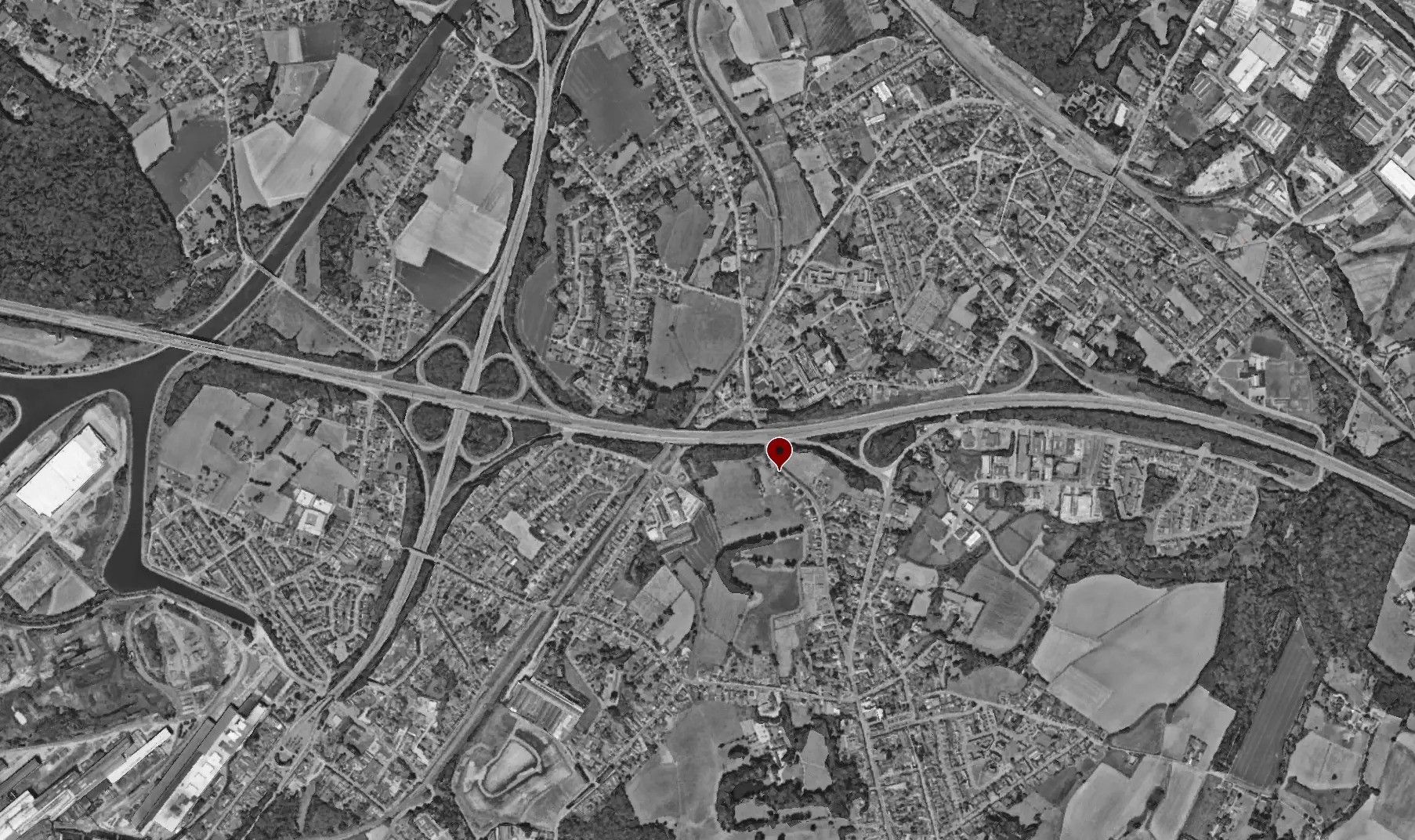 Vue aérienne en noir et blanc de Manage avec le repère rouge de l'implantation du projet