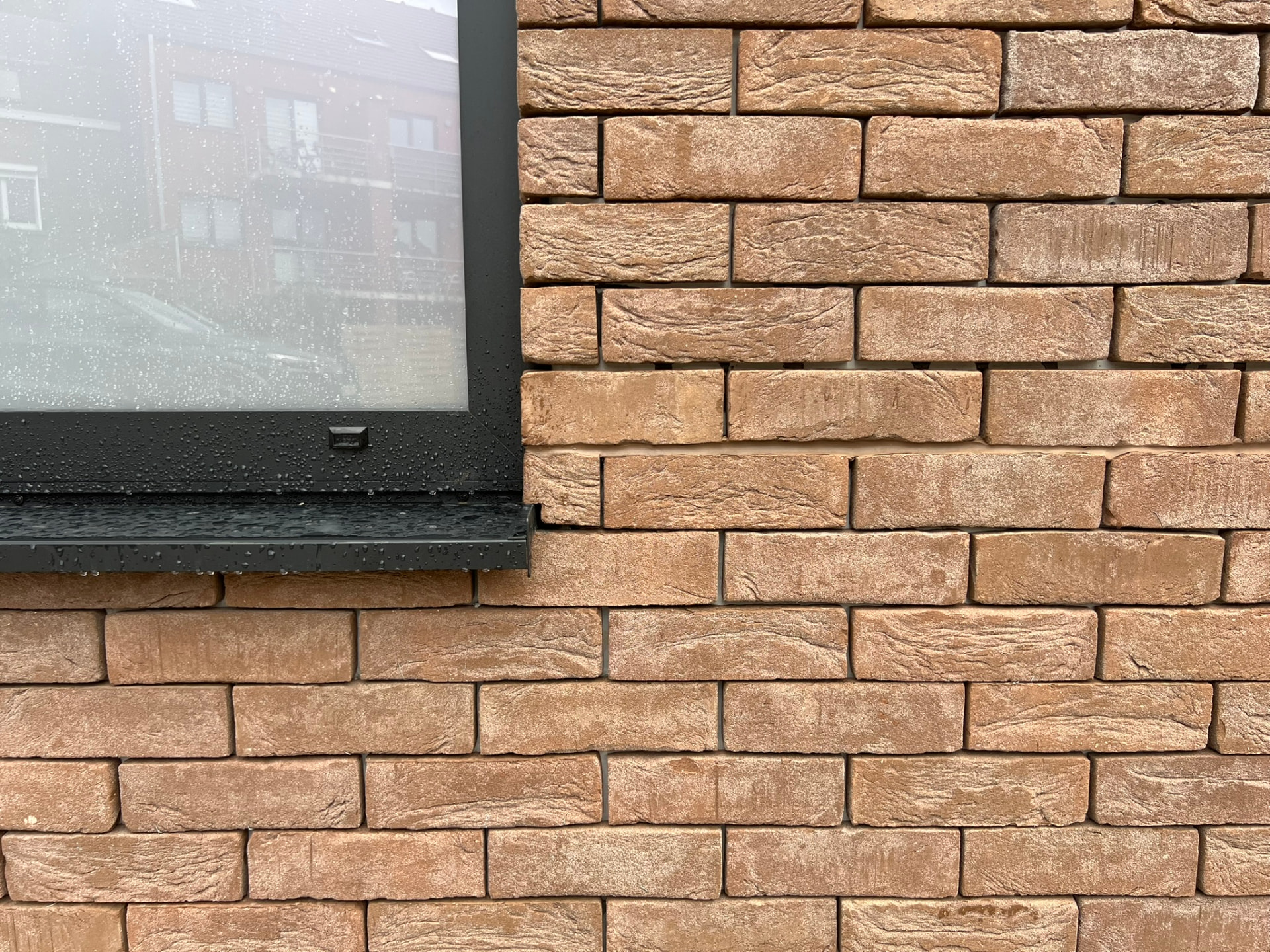 Détail de la maçonnerie en briques et du châssis noir en aluminium