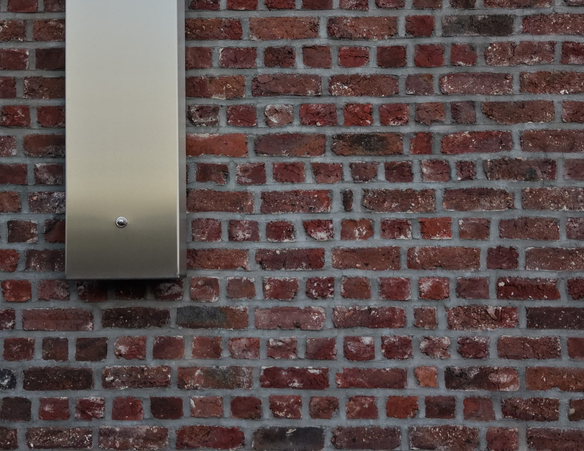 Gros plan sur un luminaire en inox fixé au mur en briques