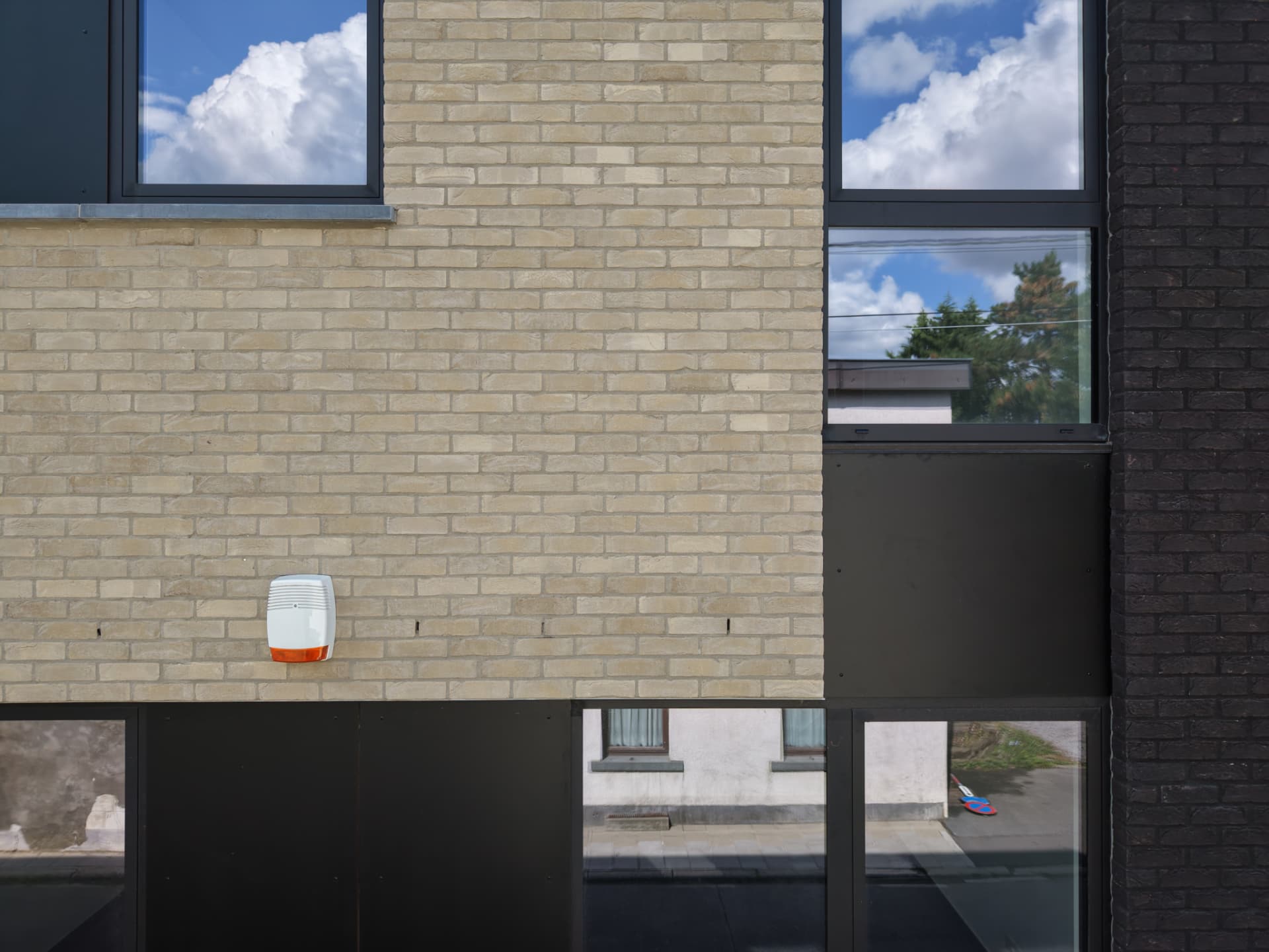 Composition de baies et de panneaux sombres sur la façade en briques claires