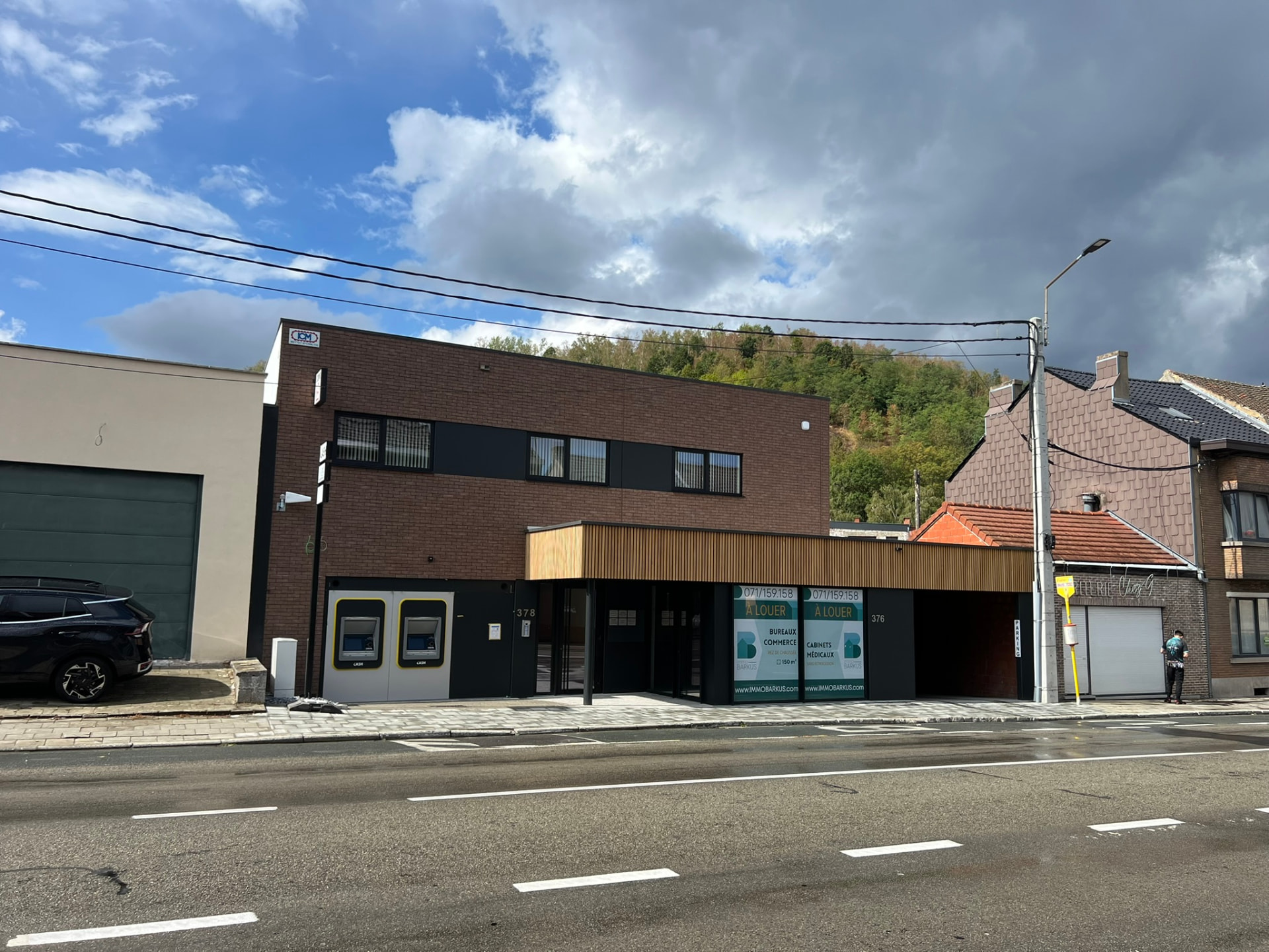Vue d'ensemble de la façade depuis la chaussée avec les logements à l'étage