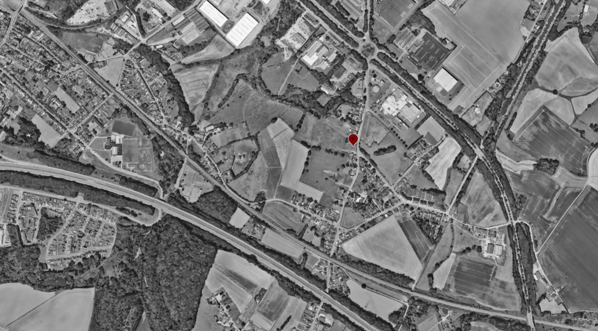 Vue aérienne en noir et blanc de Manage avec le repère rouge de l'implantation du projet