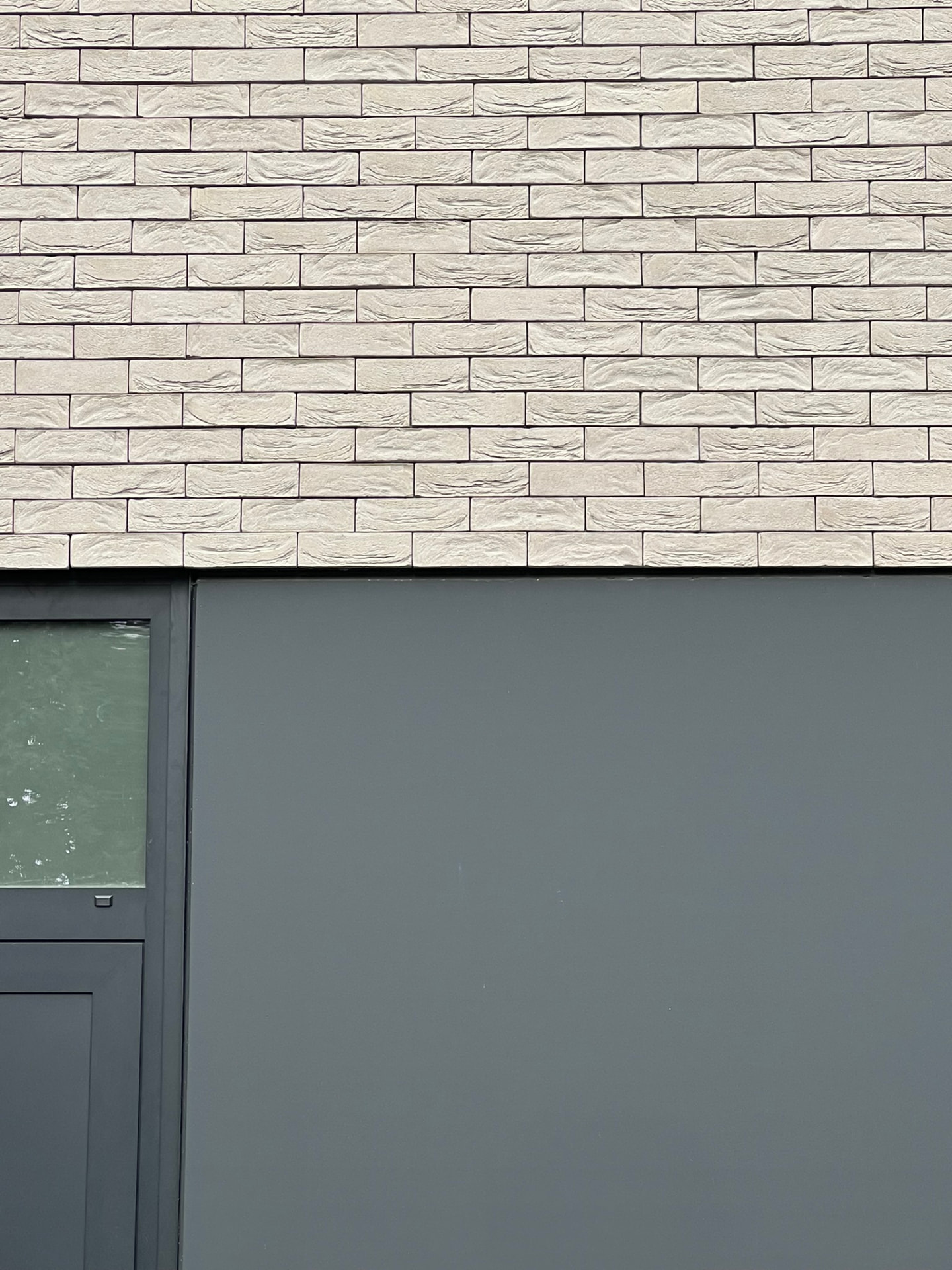 Détail de la façade : briques claires structurées et panneaux composites gris