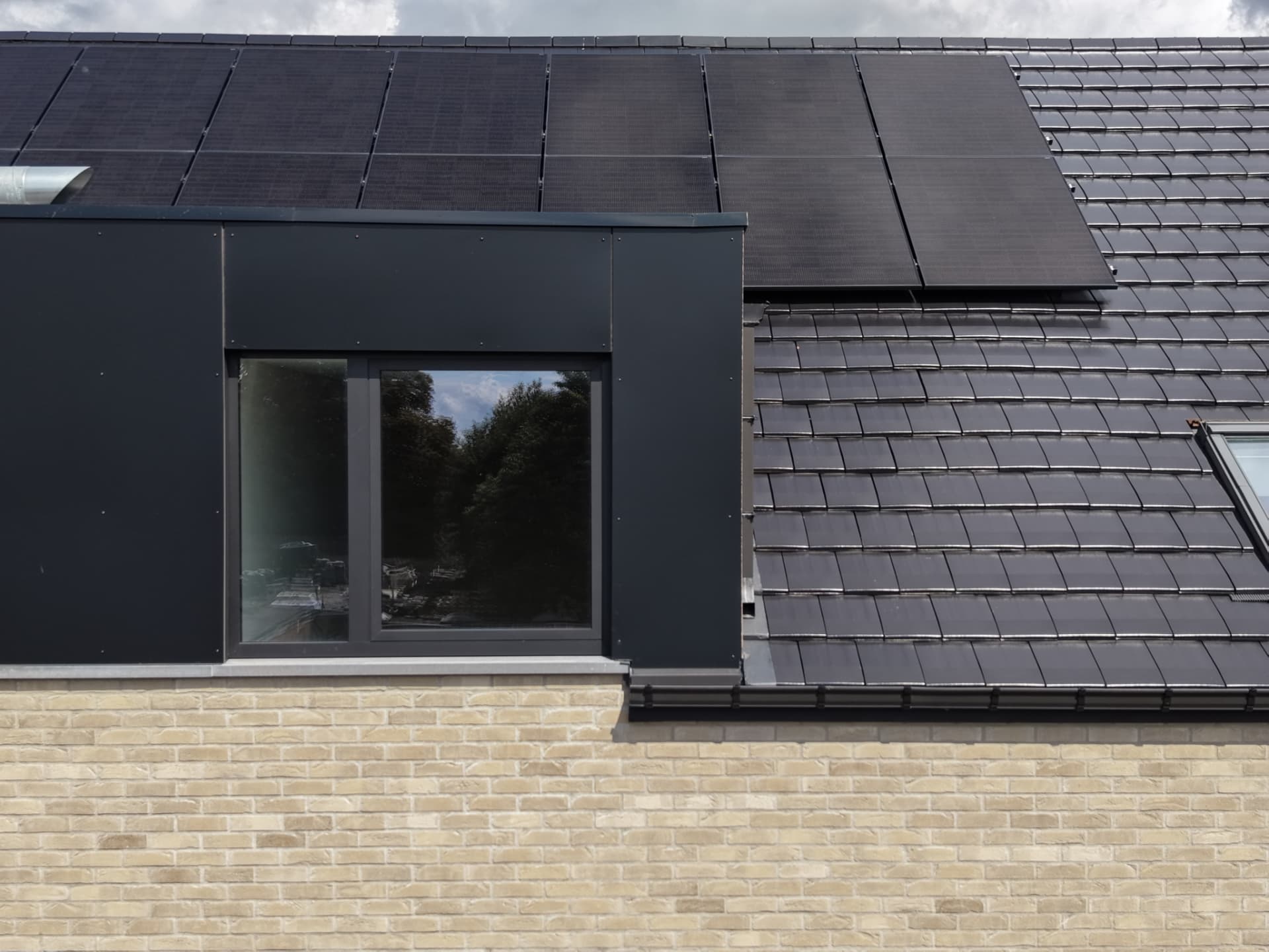 Détail de la lucarne en bardage noir et de la toiture photovoltaïque