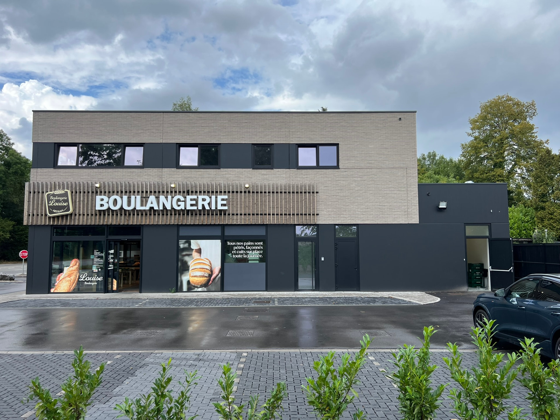 Façade principale d'un immeuble commercial contemporain en briques claires et bardage sombre