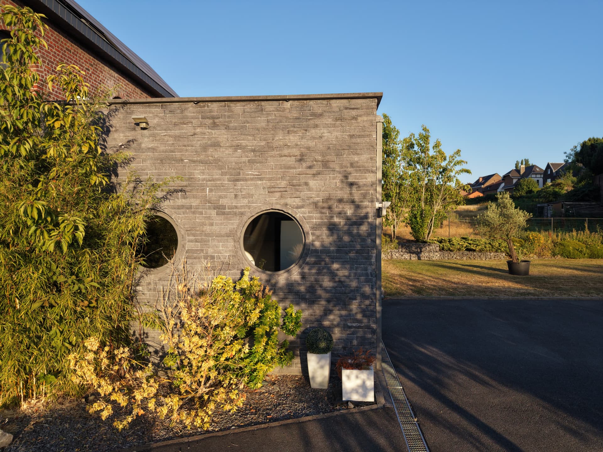 Mur contemporain en briques grises percé de deux hublots circulaires