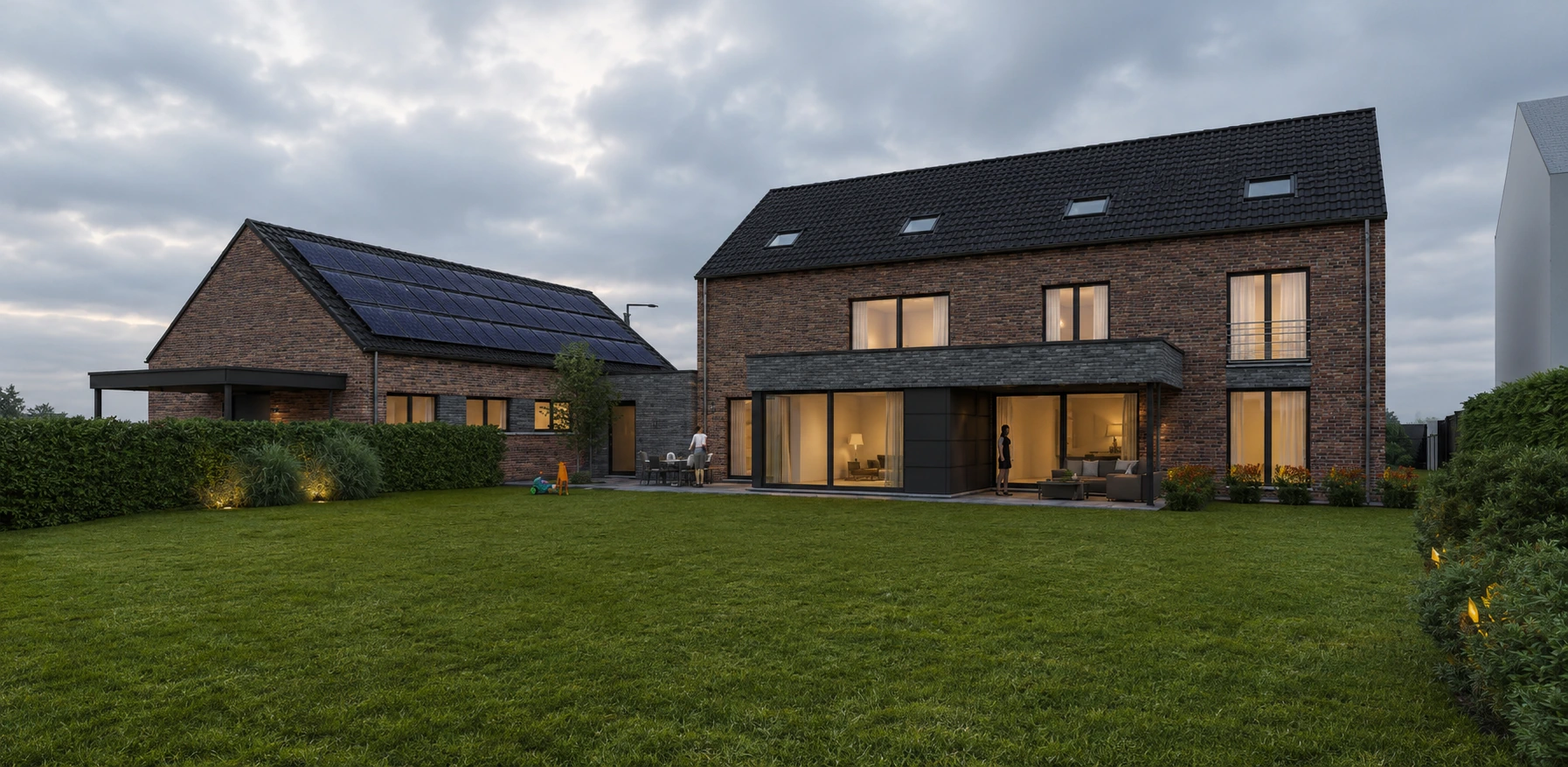 Façade jardin éclairée au crépuscule avec grandes baies vitrées et annexe solaire
