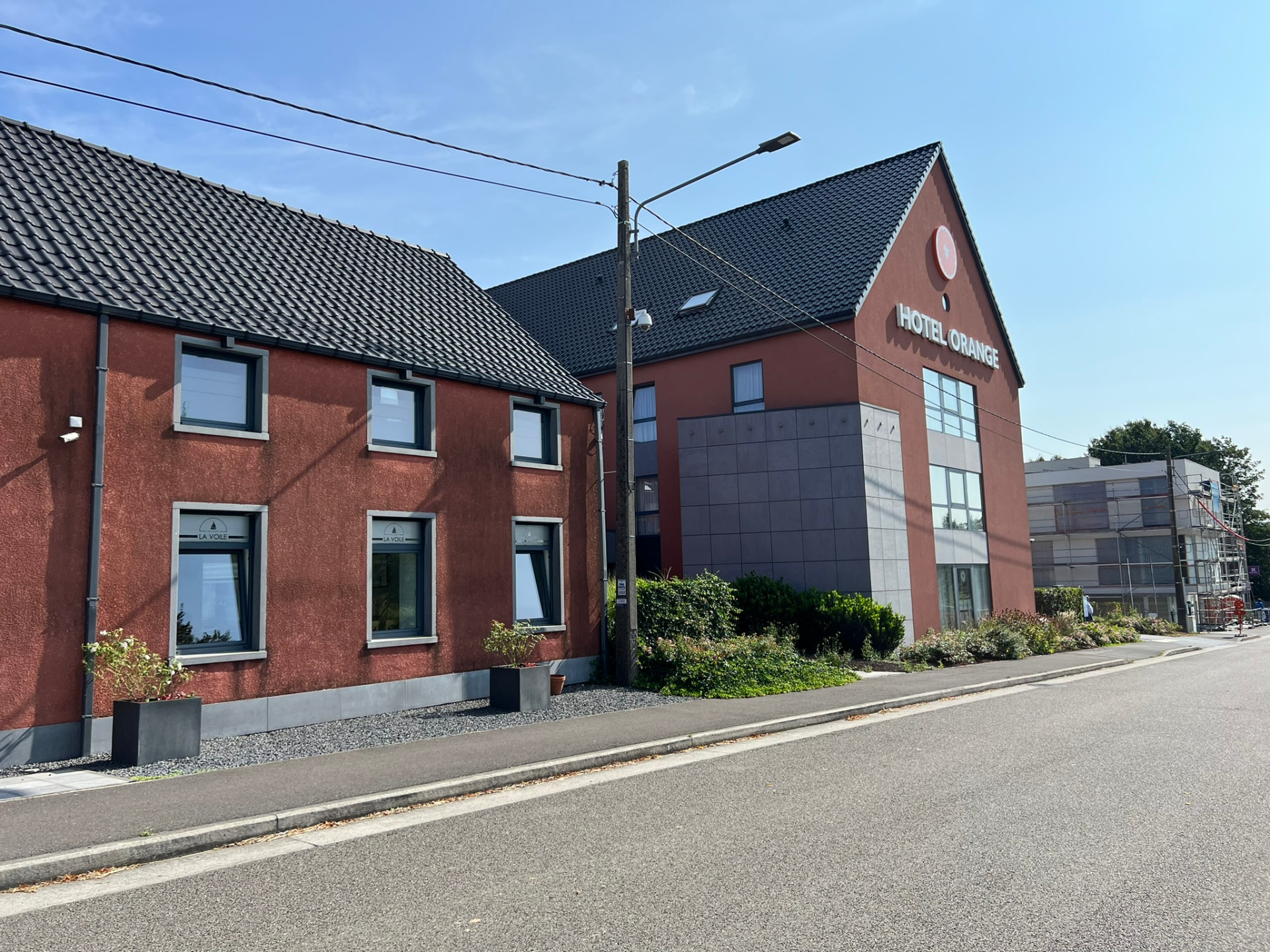 Façade sur rue de l'Hôtel Orange avec toiture en tuiles noires et volume en pierre grise